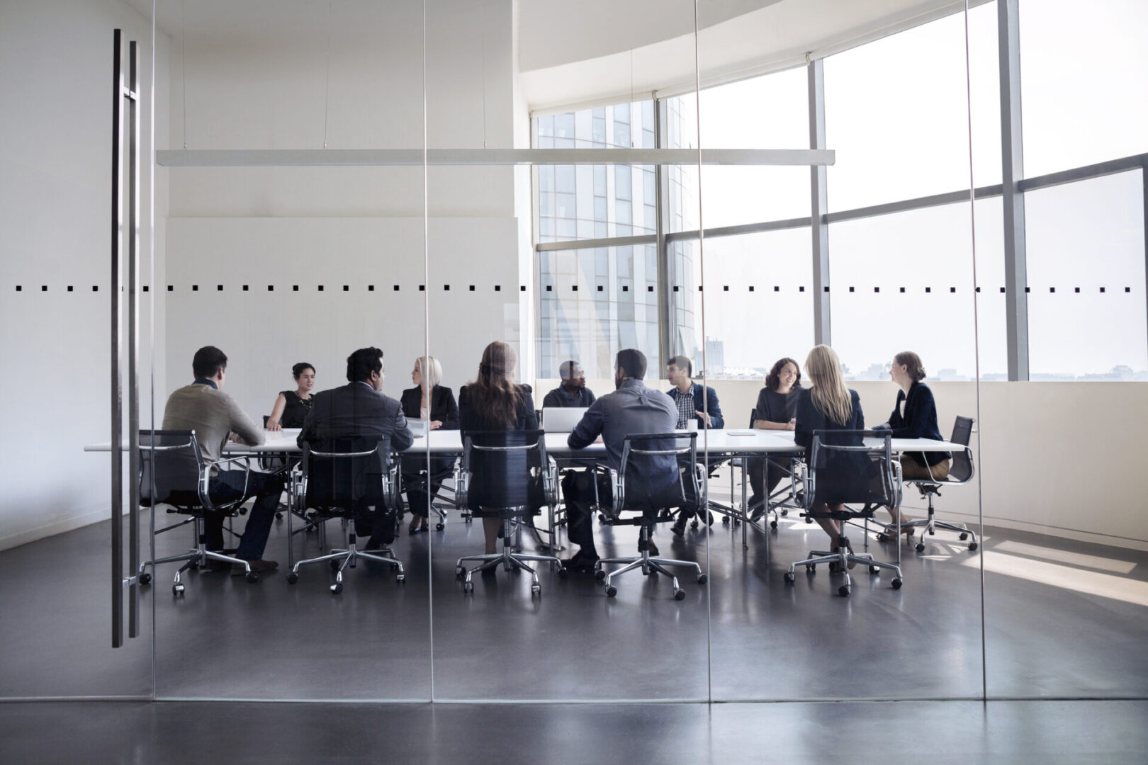 A group of people sitting at tables in front of a window.