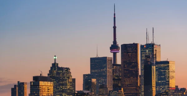Toronto skyline at sunset with the CN Tower and high-rise buildings illuminated against a pastel sky, reflecting the vibrant opportunities available to employers under Ontario's Labour Mobility Act.